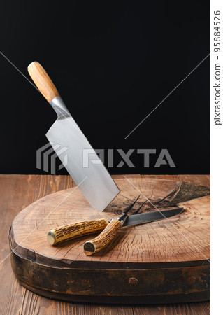 Cleaver, fork and knife on wooden blockhead 95884526