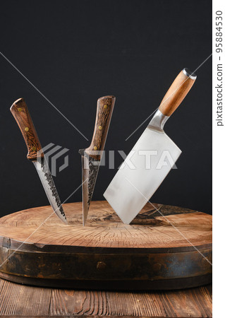 Cleaver and two meat knives sticking out of wooden blockhead 95884530