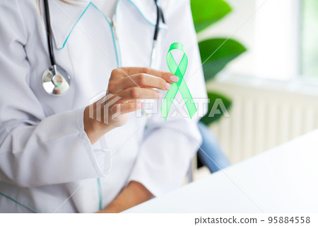 Green ribbon in hand as a symbol to awareness Lymphoma cancer 95884558