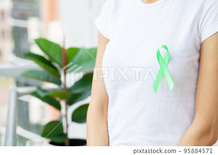 Green ribbon in hand as a symbol to awareness Lymphoma cancer 95884571