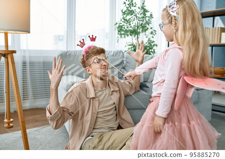 Cute little daughter with magic wand and father kidding at home 95885270