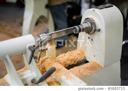 Close up view: wood turning lathe machine with shavings at workshop Close up view: wood turning lathe machine with shavings at workshop 95885715