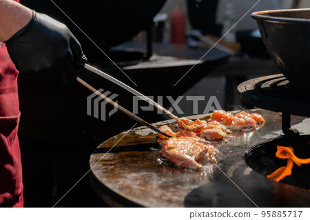 Chef cooking fried chicken meat pieces on brazier with hot flame - close up Chef cooking fried chicken meat pieces on brazier with hot flame - close up 95885717