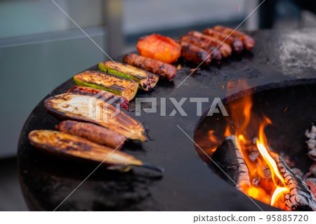 Process of cooking meat sausages, zucchini, eggplant, tomato on brazier 95885720