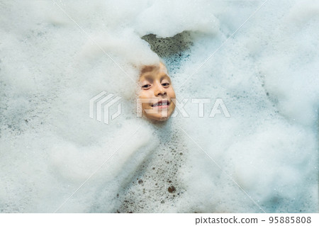 Happy little boy face swimming in the bathroom. Portrait of baby bathing in a bath full of foam 95885808