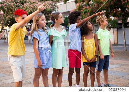 Curious preteen children pointing at something while walking outdoors Curious preteen children pointing at something while walking outdoors 95887094