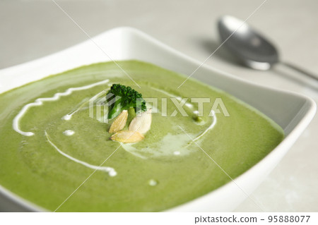 Bowl of delicious broccoli cream soup with pumpkin seeds, closeup 95888077