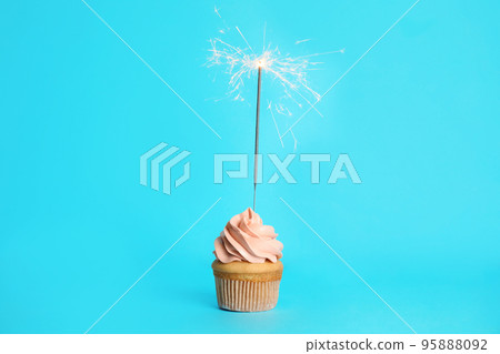 Birthday cupcake with sparkler on light blue background Birthday cupcake with sparkler on light blue background 95888092