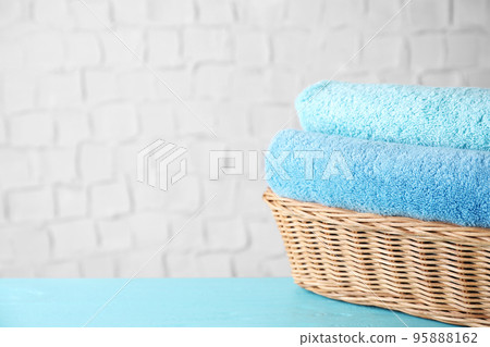 Wicker basket with clean soft bath towels on blue wooden table. Space for text 95888162