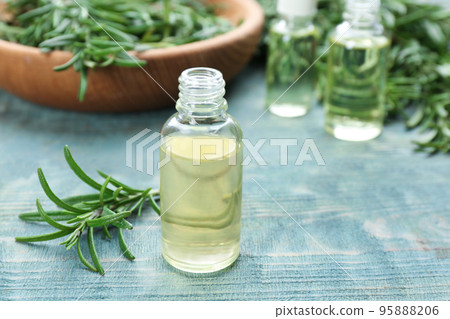 Fresh rosemary and bottle of essential oil on light blue wooden table. Space for text Fresh rosemary and bottle of essential oil on light blue wooden table. Space for text 95888206