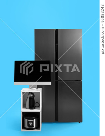 Modern refrigerator and other household appliances on blue background Modern refrigerator and other household appliances on blue background 95888248
