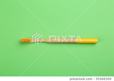 Natural bamboo toothbrush on green background, top view Natural bamboo toothbrush on green background, top view 95888309