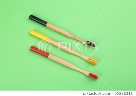 Natural bamboo toothbrushes on green background, flat lay Natural bamboo toothbrushes on green background, flat lay 95888311