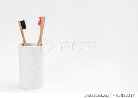 Bamboo toothbrushes in holder isolated on white Bamboo toothbrushes in holder isolated on white 95888317