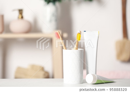 Bamboo toothbrushes and paste on light table indoors. Space for text Bamboo toothbrushes and paste on light table indoors. Space for text 95888320