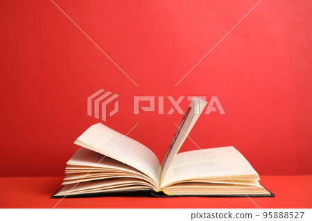 Open old hardcover book on red background. Space for text 95888527