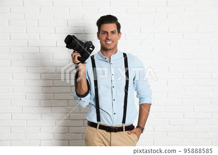 Professional photographer working near white brick wall in studio Professional photographer working near white brick wall in studio 95888585