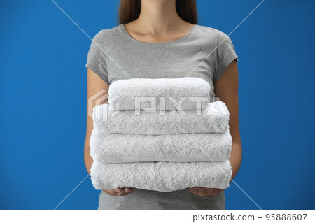 Woman holding fresh towels on blue background, closeup Woman holding fresh towels on blue background, closeup 95888607