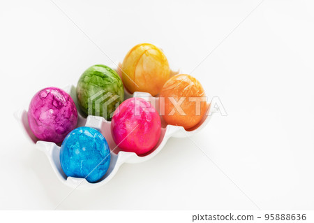 Colorful six Easter eggs in porcelain storage organizer box on white background. Easter celebration concept. Close up, copy space 95888636