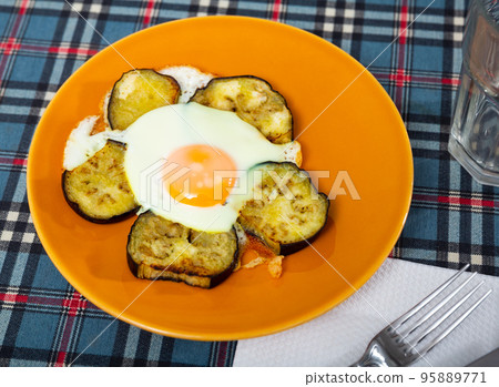 Fried eggs with liquid yolk and slices of aubergine on plate Fried eggs with liquid yolk and slices of aubergine on plate 95889771