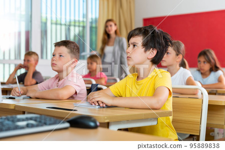 Schoolkids sitting at desks 95889838
