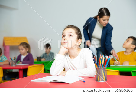 Tired schoolgirl at pupils desk at lesson 95890166