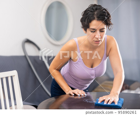 Woman is cleaning surface on table 95890261