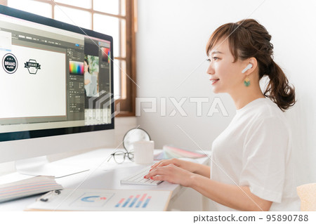 Asian designer woman working while listening to music with earphones 95890788