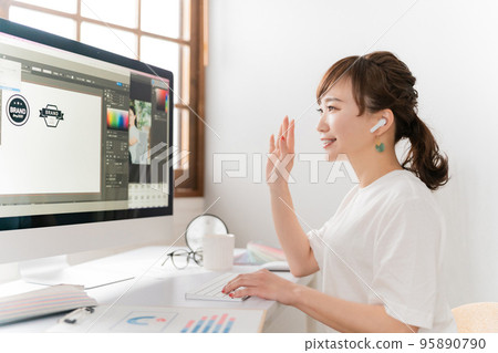 A designer Asian woman who has an online meeting / WEB conference using earphones 95890790