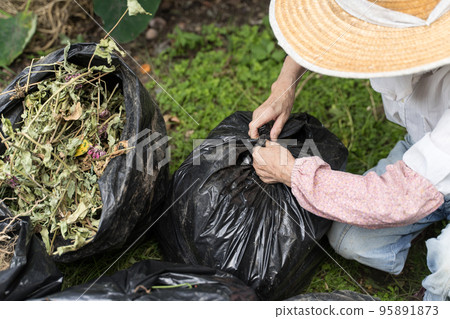 Senior woman tying a trash bag Senior woman tying a trash bag 95891873