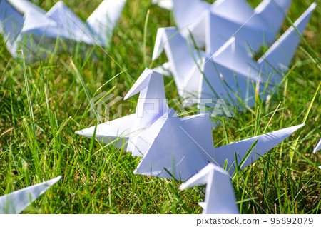 Japanese folded Origami cranes on fresh grass. Hundreds handmade paper birds on green field with copy space. 1000 thousand crane tsuru sculpture topic. Symbol of peace, faith, health, wishes and hope  95892079