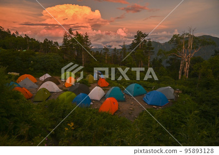 In August, the Northern Alps of the summer mountain seen from the ridgeline of Mt. Nishihodaka under fine weather and a tent night, summer-like cumulonimbus clouds illuminated by the setting sun In August, the Northern Alps of the summer mountain seen from the ridgeline of Mt. Nishihodaka under fine weather and a tent night, summer-like cumulonimbus clouds illuminated by the setting sun 95893128