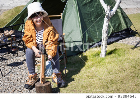 Solo camp Woman splitting firewood Solo camp Woman splitting firewood 95894643
