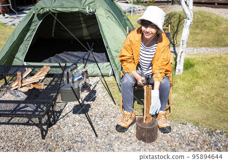 Solo camp Woman splitting firewood Solo camp Woman splitting firewood 95894644