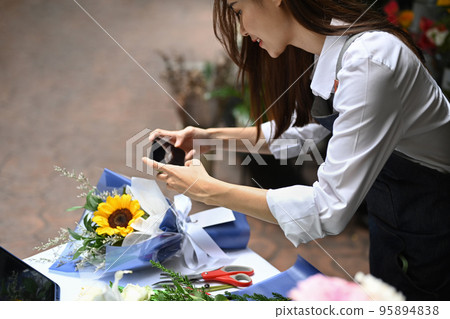 Photo of female florist creating beautiful bouquet of colorful different flowers in her floral shop. Business, sale and floristry concept Photo of female florist creating beautiful bouquet of colorful different flowers in her floral shop. Business, sale and floristry concept 95894838