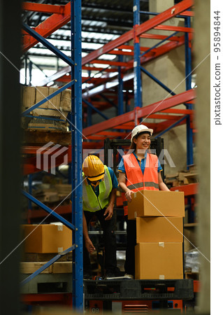 Warehouse workers working in the retail warehouse full of shelves with goods. Manufacture storehouse occupation concept Warehouse workers working in the retail warehouse full of shelves with goods. Manufacture storehouse occupation concept 95894844