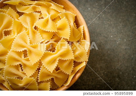 Dry uncooked farfalle pasta in bowl 95895899