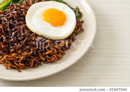 dried Korean spicy black sauce instant noodles with fried egg and kimchi 95897084
