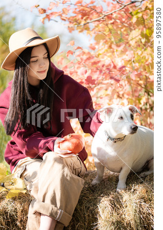 Teenager girl playing with dog in autumn garden Teenager girl playing with dog in autumn garden 95897580