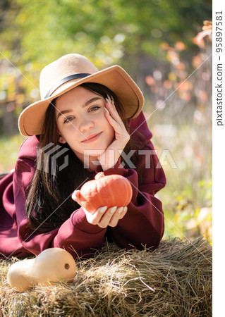 Happy young girl with pumpkin in autumn garden 95897581