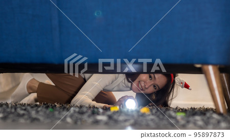 Woman with a flashlight looking under the bed. Woman with a flashlight looking under the bed. 95897873