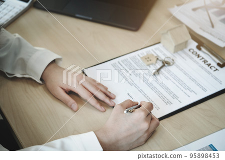 The customer is holding a pen and is reading the housing purchase contract before signing it 95898453