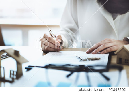 The customer is holding a pen and is reading the housing purchase contract before signing it The customer is holding a pen and is reading the housing purchase contract before signing it 95898502