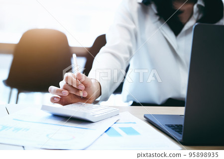 Business owners use calculators to calculate with financial documents to analyze third-party profits to invest in company stocks 95898935