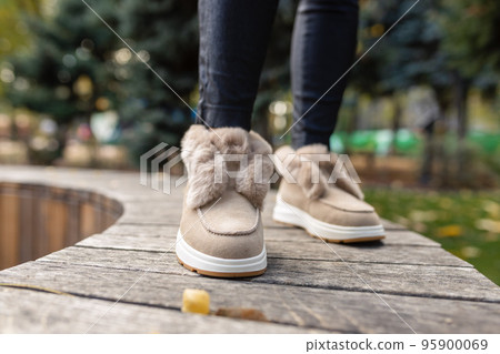 Stylish trendy beige autumn-winter shoes with soft light fur and rhinestones on the gray paving stones 95900069