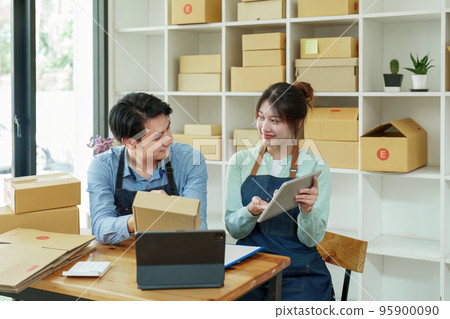 Portrait of a small start-up and SME owner, an Asian male and female entrepreneur checking orders and packing for customers, self-employed, freelance, online selling. 95900090