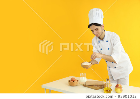 Concept of cooking, young man chef on yellow background Concept of cooking, young man chef on yellow background 95901012
