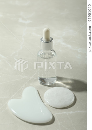 Face care concept with gua sha and cosmetic on light textured background 95901040