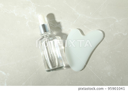 Face care concept with gua sha and cosmetic on light textured background 95901041