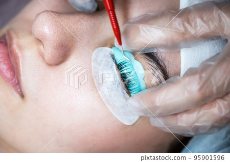 The master uses a multifunctional tool for laminating eyelashes. 95901596